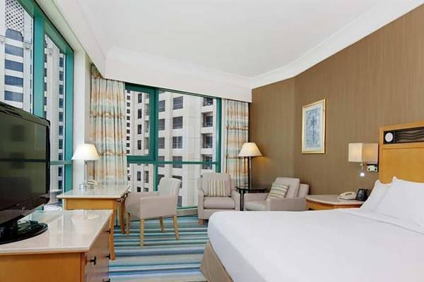 Hotelzimmer im Hilton Dubai Jumeirah Resort mit Fernseher, Schreibtisch und Sesseln.
