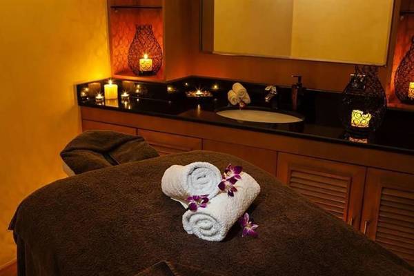 Spa-Behandlungsbereich im Hilton Dubai Jumeirah Resort mit Kerzen, Handtüchern und einer Massageliege.