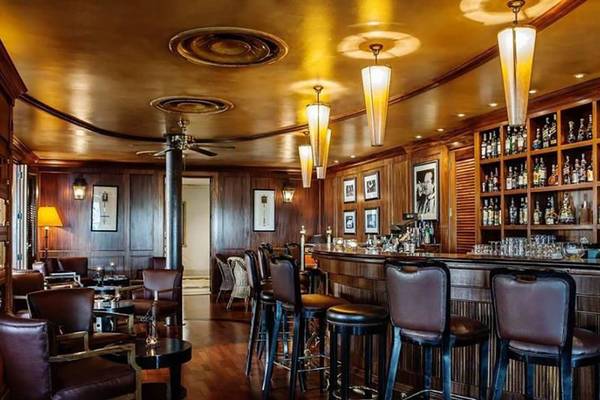 Innenansicht der Bar im Hilton Dubai Jumeirah Resort mit Holzelementen, Barhockern und Flaschenregal.