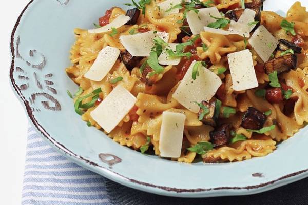 Nahaufnahme von Pasta mit Pilzen und Tomaten auf einem blauen Teller