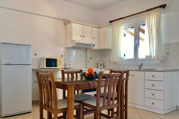 Küche im Bruskos Hotel & Suites mit Kühlschrank, Mikrowelle und Esstisch.