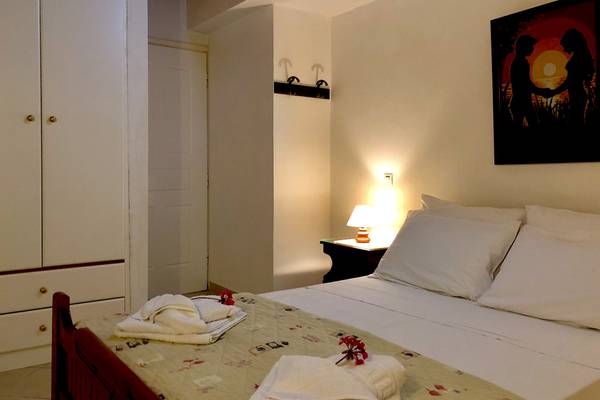 Schlafzimmer im Bruskos Hotel & Suites mit Bett, Nachttisch, Lampe und Gemälde an der Wand.