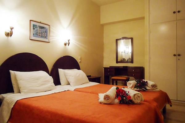 Doppelzimmer im Bruskos Hotel & Suites mit zwei Betten, Blumen und Möbeln.
