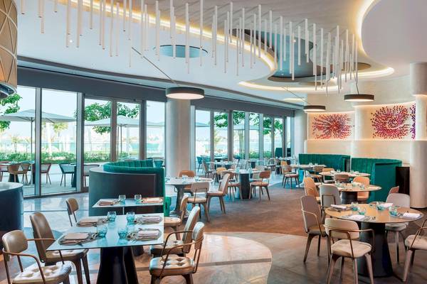 Innenansicht des Restaurants im W Dubai - The Palm mit modernen Möbeln und Glaswänden.
