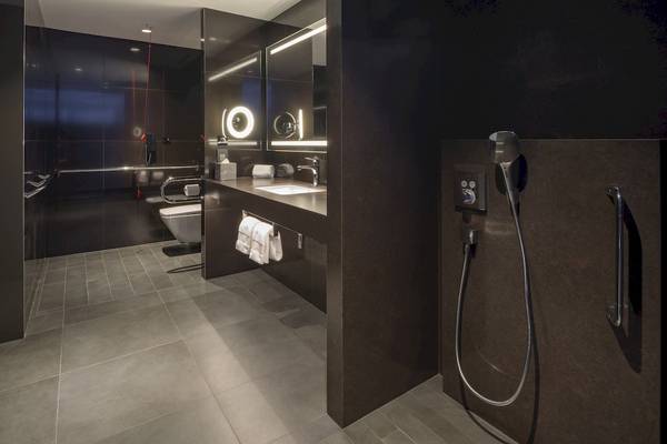 Badezimmer im W Dubai - The Palm Hotel mit schwarzen Wänden, gefliestem Boden und moderner Duschvorrichtung.