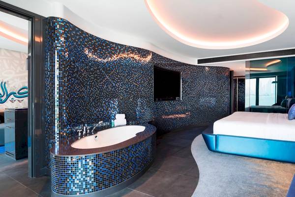 Das Badezimmer der Suite im W Dubai - The Palm mit blauen Fliesen und einer Badewanne.