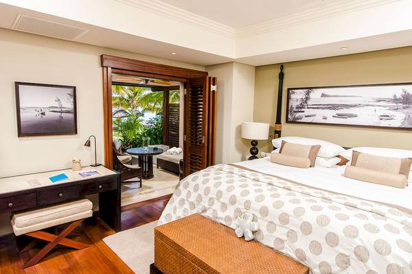 Schlafzimmer im LUX Le Morne Hotel mit Doppelbett und Blick auf den Garten.