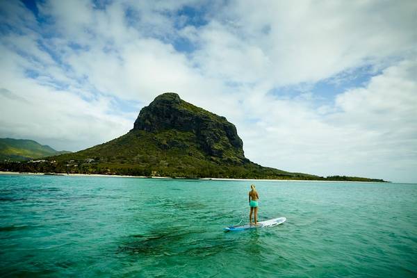 Frau beim Paddelsurfen vor dem LUX Le Morne Hotel mit Blick auf den Le Morne Berg