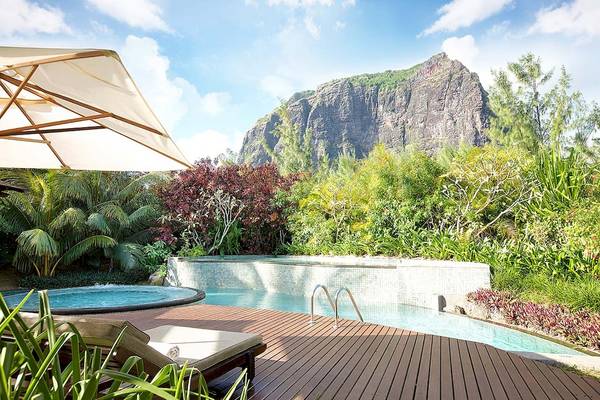 Pool-Terrasse des LUX Le Morne Hotels mit einem großen Felsen im Hintergrund.