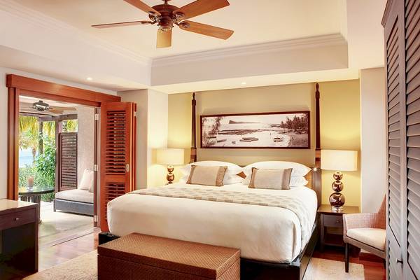 Schlafzimmer im LUX Le Morne Hotel mit einem großen Bett, Meerblick und deckenventilator.