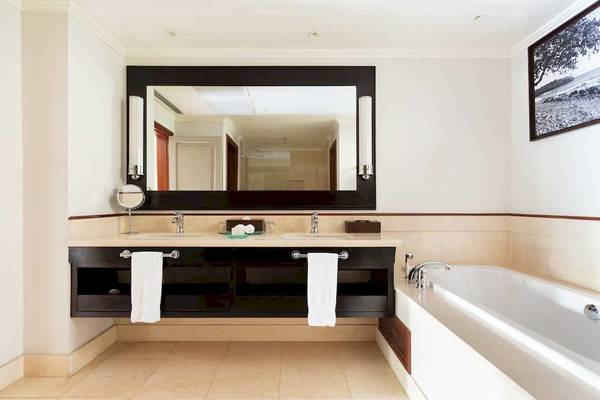 Badezimmer im LUX Le Morne Hotel mit Doppelwaschbecken, Spiegel und Badewanne.