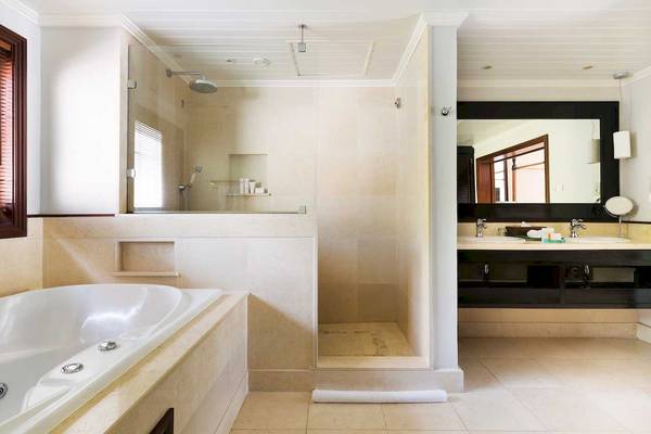 Badezimmer im LUX Le Morne Hotel mit Badewanne, Dusche und Waschbecken.