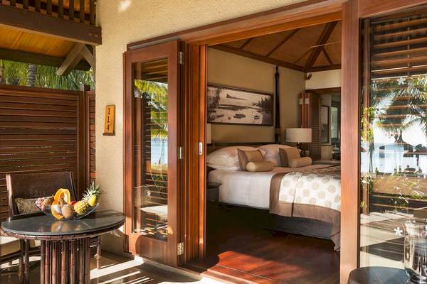 Suite im LUX Le Morne mit Blick auf das Meer, Bett und Tisch mit Früchten.