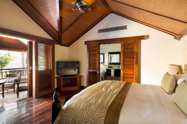 Schlafzimmer im LUX Le Morne Hotel mit Bett, Fernseher und Balkonzugang