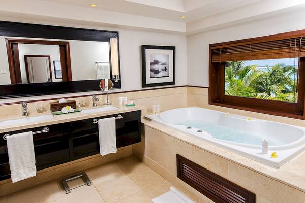 Badezimmer im LUX Le Morne Hotel mit Badewanne und Ausblick auf den Ozean.