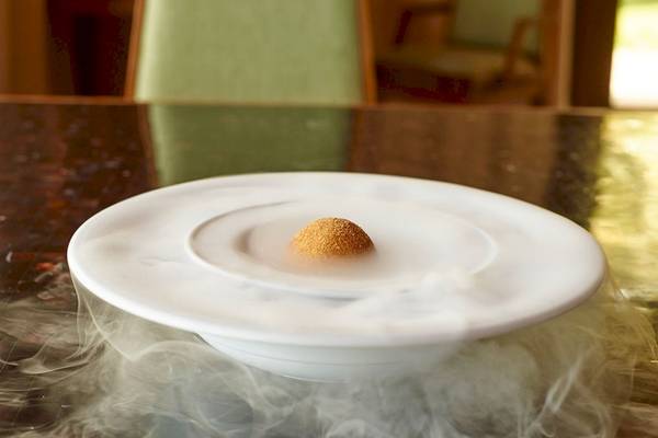 Ein weißer Teller mit rauchigen Effekten, auf dem ein Dessert serviert wird.