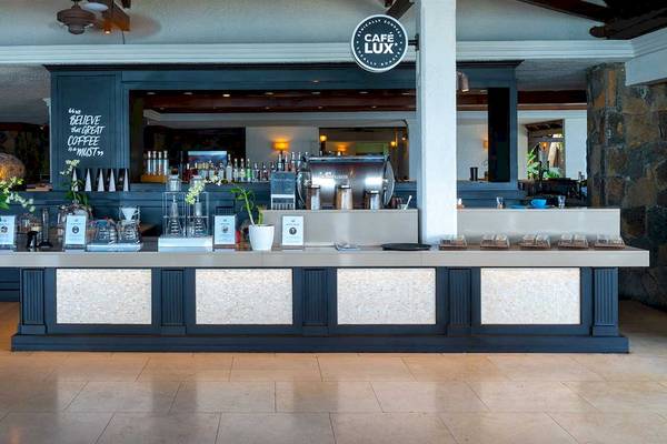 Die Bar des Café LUX im Hotel LUX Le Morne mit Thekenbereich und Getränken.