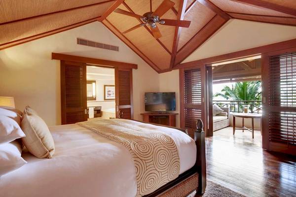 Lux Le Morne Hotel Schlafzimmer mit Bett, Fernseher und Balkon.