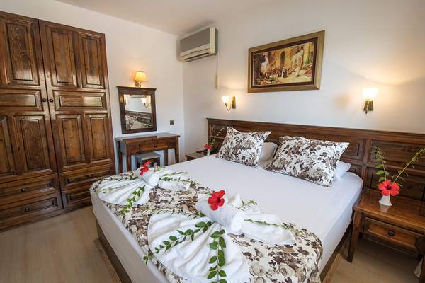 Schlafzimmer im Pirat Hotel mit blumigem Bettwäsche-Arrangement und Holzmöbeln.