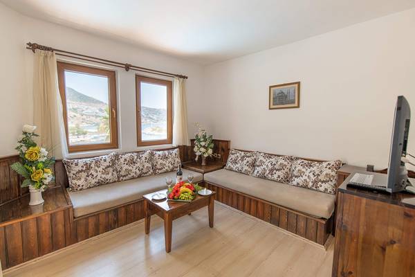 Wohnzimmer im Pirat Hotel mit zwei Sofas, Tisch, Fenstern und Bergblick.