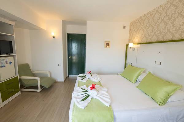 Schlafzimmer im Pirat Hotel mit einem Bett, grünen Kissen und Blumendekoration.