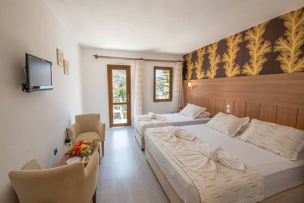 Innenansicht eines Doppelzimmers im Pirat Hotel mit zwei Betten, Fernseher, Tisch mit Obstteller, Stühle und Fenster mit Balkon