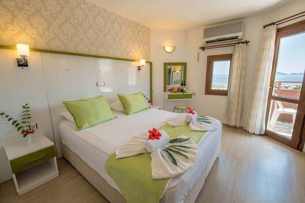 Schlafzimmer im Pirat Hotel mit Blick auf das Meer, Bett mit grünen Kissen und weißen Handtüchern.