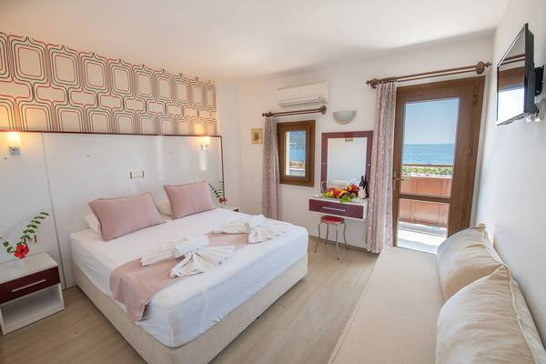 Schlafzimmer im Pirat Hotel mit Meerblick, Bett, Sofa, Nachttischen und Fernseher.