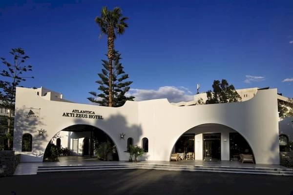Vorderansicht des Atlantica Akti Zeus Hotels mit zwei bogenförmigen Eingängen und Palmen im Hintergrund.