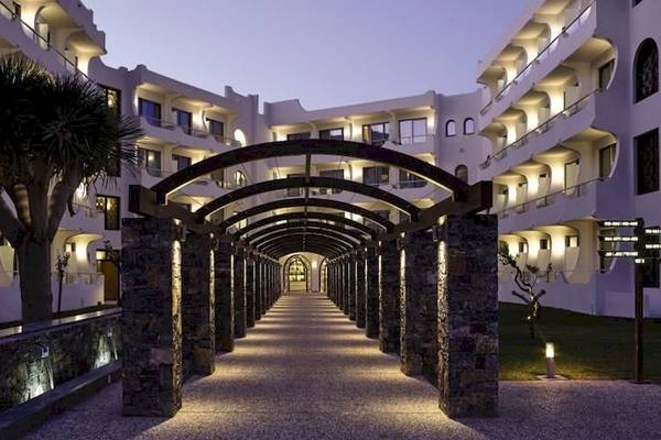 Beleuchteter Eingang des Atlantica Akti Zeus Hotels mit Arkaden und Gehweg.