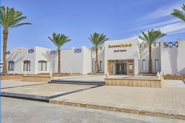 Außenansicht des Solymar Reef Marsa Hotels mit weißen Gebäuden und Palmen im Vordergrund.