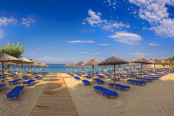 Lagomandra Strand mit vielen blauen Sonnenliegen und Sonnenhuten unter einem blauen Himmel