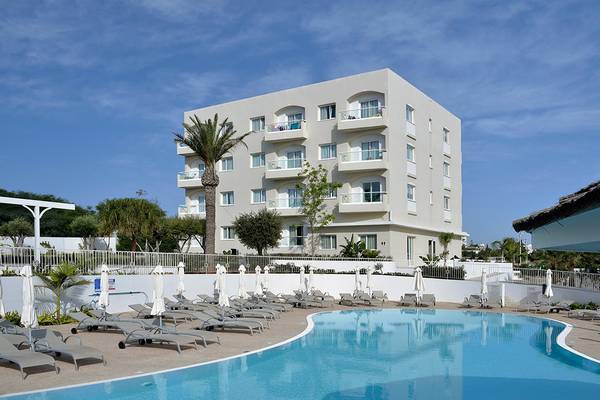 Außenpoolbereich des Sunrise Gardens Hotels mit weißen Liegestühlen und einem großen Gebäude im Hintergrund.