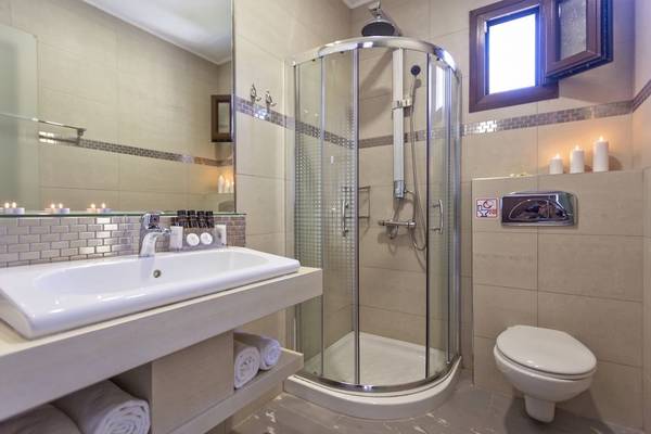 Badezimmer mit Dusche, Toilette, Waschbecken und Kerzen.