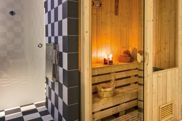 Sauna im Lagomandra Beach Hotel mit Holzwänden, Kerzen und einem Eimer.
