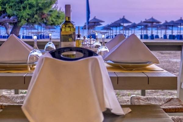 Ein Tisch am Strand im Lagomandra Beach Hotel mit Gläsern und Weinflasche.