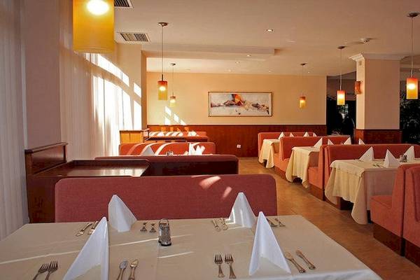 Innenbereich des Restaurants im Riviera Beach Hotel mit gepolsterten roten Sitzen und weiß gedeckten Tischen.