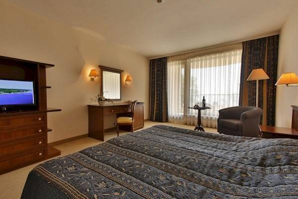 Zimmer im Riviera Beach Hotel mit Doppelbett, Fernseher, Schreibtisch und Stühle.
