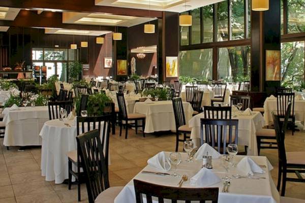 Innenansicht des Restaurants im Riviera Beach Hotel mit gedeckten Tischen und Stühlen.
