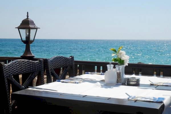 Tisch mit Meerblick im Riviera Beach Hotel, gedeckt mit Tischdecke, Besteck und Blumen.