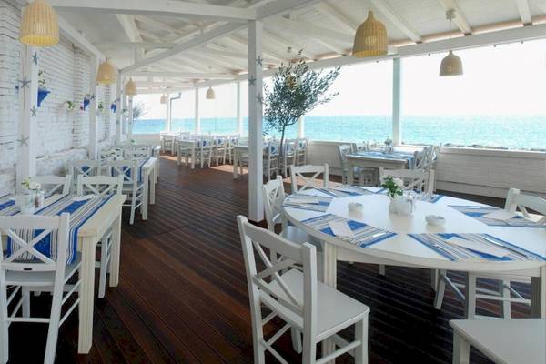 Terrasse des Riviera Beach Hotels mit Blick auf das Meer und weißen Möbeln.