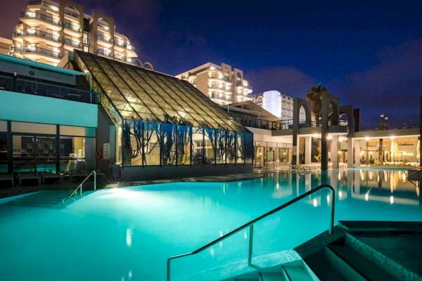 Ein Swimmingpool in AX Odycy Hotel im Freien mit einer Glasüberdachung und moderner Architektur im Hintergrund bei Nacht.