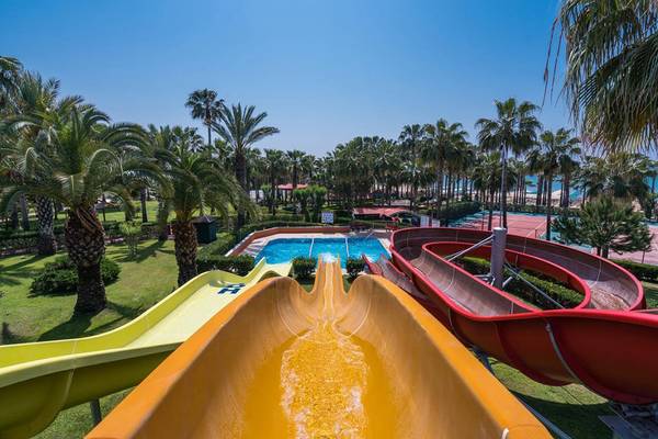 Wasserrutschen im Freien im Miramare Queen Hotel, umgeben von Palmen und einem Pool.