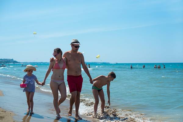 Eine Familie, die am Strand spazieren geht, genießt einen sonnigen Sommertag.