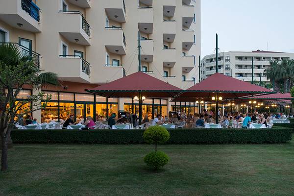 Miramare Queen Hotel Außenterrasse mit Gästen und roten Sonnenschirmen.
