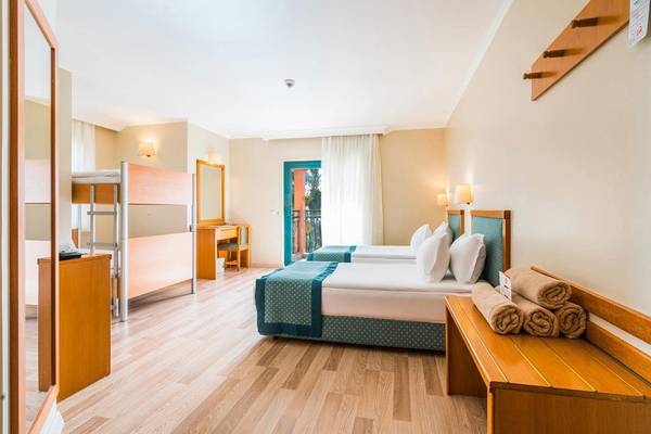 Innenansicht des Miramare Queen Hotels mit zwei Betten, Schreibtisch und Balkontür.