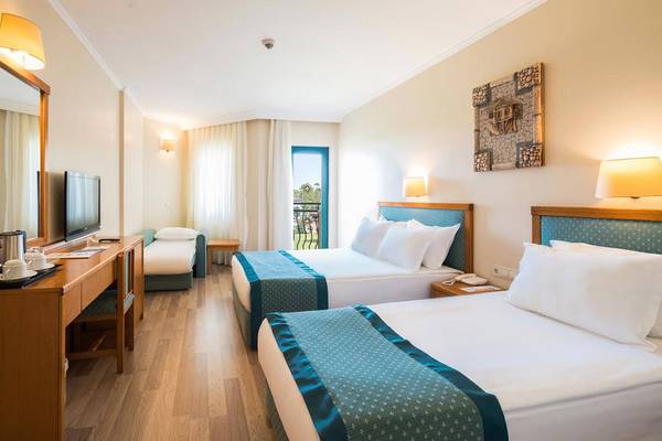 Zwei Doppelbetten in einem geräumigen Hotelzimmer des Miramare Queen, mit einem Schreibtisch und Fernseher.