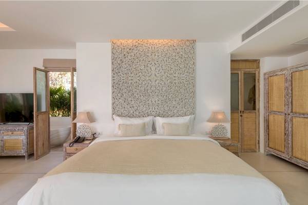 Schlafzimmer im Eden Beach Khao Lak Resort & Spa mit einem großen Bett, zwei Nachttischen und einer Fernsehwand.