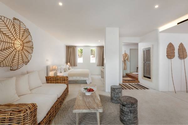 Innenansicht des Eden Beach Khao Lak Resort & Spa mit Wohnzimmer, Couch, Tisch und Bett.