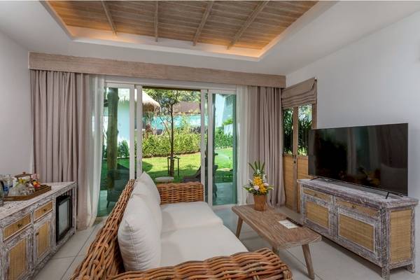 Eden Beach Khao Lak Resort Wohnzimmer mit großer Couch und Fernseher vor großen Fenstern.